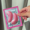 Een vrouw pakt de Vitamin B12 oogmaskers van Australian Bodycare uit, verwijdert het beschermfolie en plaatst voorzichtig de roze patches onder haar ogen, waarna ze ze comfortabel gladstrijkt.