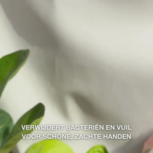 Close-up van handen die heldere, lichtblauwe, schuimende vloeibare handzeep met Tea Tree Oil in de palm pompen en deze zachtjes uitsmeren over handpalmen, handruggen en tussen de vingers — de zachte, reinigende schuim verwijdert bacteriën en vuil en maakt de huid zacht en gehydrateerd.